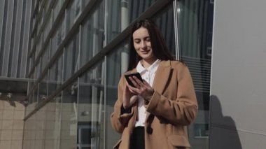 Güzel bir iş kadını akıllı telefon mesajları kullanıyor şirket ofisinde yürüyor cep telefonunda kısa mesajlar yazıyor e-postalarını kontrol ediyor 4k görüntülerinde başarılı kadın yöneticiler.