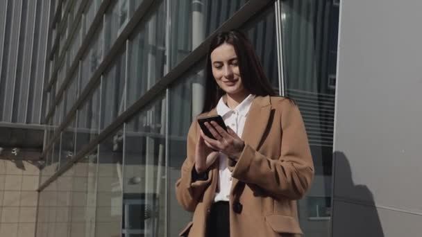 아름다운 비지니스 스마트폰 메시지를 사용하여 사무실에서 걸어다니며 전화로 메시지를 입력하는 — 비디오