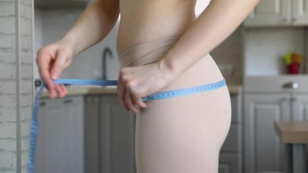 Meisje meten taille met blauw lint voor de spiegel — Stockvideo