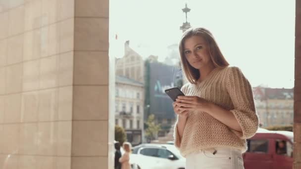 Adulto caucasico fiducioso giovane donna d'affari sta utilizzando Smartphone App al di fuori vicino a Modern Office Building. Basso angolo medio 4K al rallentatore Colpo aziendale con fotocamera in movimento — Video Stock