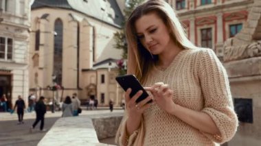 Kredi kartı ve telefon esmer kadın bankta oturan sokakta Öğrenci ve akıllı telefon banka kartından Internet üzerinden online ödeme yapar