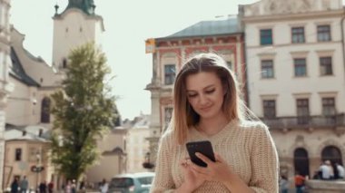 Kendine güveni tam bir iş kadını, modern iş alanının yakınındaki otoparkta yürüyor. Genç sarışın kadın Smartphone 'da mesaj atıyor.