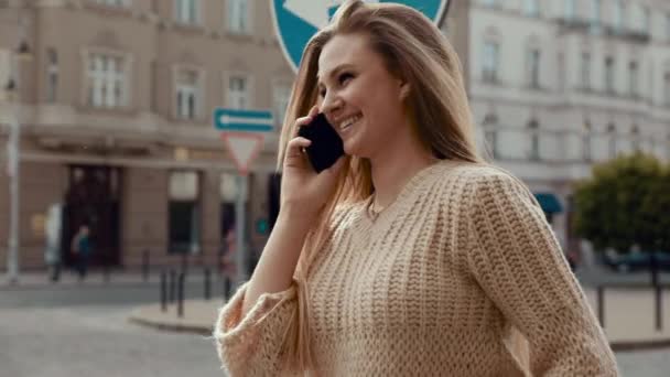 Ritratto di giovane donna attraente Vestito elegante che cammina all'aperto, parlando sul suo smartphone. Avere buon gusto nei vestiti. Sorridendo mentre fai conversazione telefonica. Ragazza in cappello nero . — Video Stock