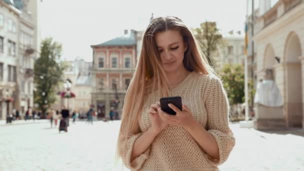 Nahaufnahme erfolgreiche Geschäftsfrau mit Telefon auf der Straße. ernsthafte Geschäftsfrau, die mit Telefon im Freien spazieren geht. sexy Frau Nachrichten am Telefon auf der Straße. Unternehmerin arbeitet mit Smartphone — Stockvideo