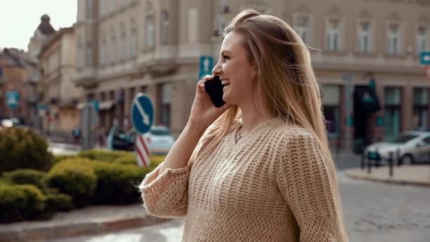 Aantrekkelijke vrouw typt berichten op haar smartphone tijdens een wandeling in de straat. Plezier hebben en genieten van de tijd buiten. Mooi blond met Smartphone voor de camera. Mooi meisje. — Stockvideo