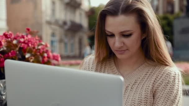 Mujer joven pensativa en gafas escribe algo en su computadora portátil y siente dolor de cabeza — Vídeos de Stock