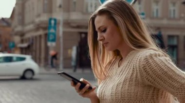 Caddede yürüyen ve cep telefonu kullanan büyüleyici gülüşlü güzel kadın. Modern güneş gözlüğü takmak ve şık kıyafetler giymek. Sıradan giyimli, çekici bir kadın.