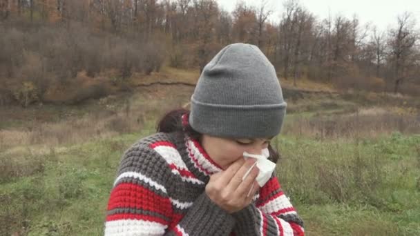 Young beautiful woman stands and sneezes outdoors in autumn cold day. — Stock Footage Young beautiful woman stands and sneezes outdoors in autumn cold day. Stock Footage