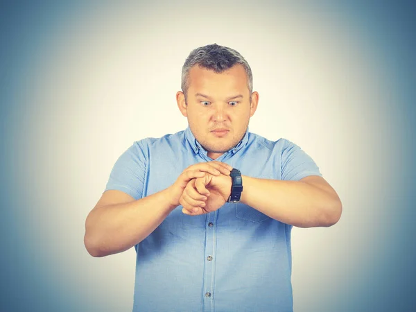 Fat businessman late for work, looking at his watch