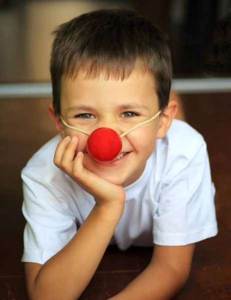 Retrato de um menino feliz com um nariz de palhaço — Fotografia de Stock