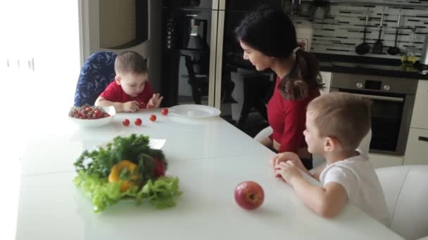 Дети с няней едят фрукты и улыбаются за столом . — стоковое видео