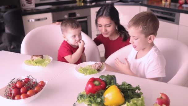 Kinder mit Babysitter essen Obst und lächeln am Tisch. — Stockvideo