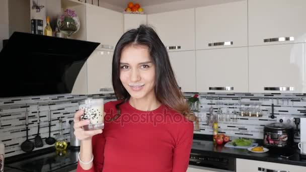 Молодая красивая стройная спортивная женщина пьет йогурт и улыбается в камеру — стоковое видео