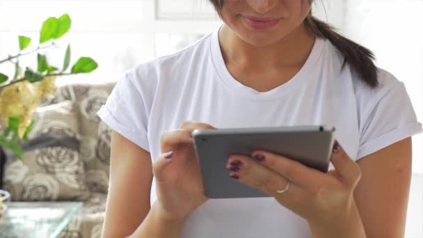 Niña caucásica en camiseta blanca usando una tableta — Vídeos de Stock