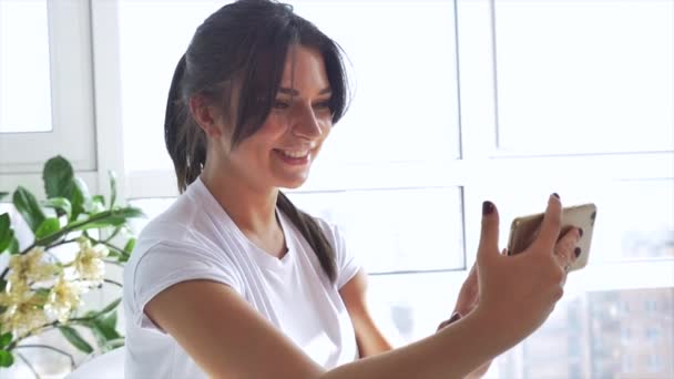 Fille blanche en t-shirt blanc faire selfie à l'aide d'un smartphone — Video