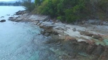 Hava. Okyanus kıyıları tropikal kayaların üzerinde duran genç kadın.