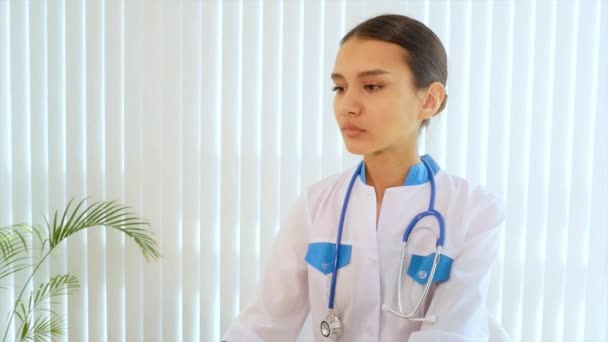 Amistosa doctora sonriendo en la recepción. El personal médico dice hola. — Vídeos de Stock