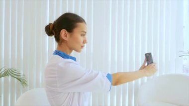 Genç çekici kadın doktor selfie bir cep telefonu ile yapıyor 