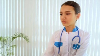 Doktor tıbbi bir elbise giyiyor, bir stetoskop boynunda asılı.