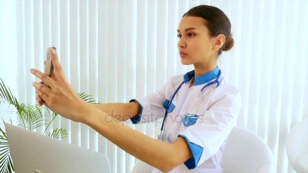 Joven atractiva doctora haciendo selfie con un teléfono móvil . — Vídeos de Stock