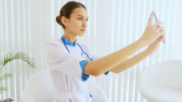 Young attractive female doctor doing selfie with a mobile phone. — Stock Video