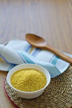 Millet beyaz bir fincanda yuvarlak bir hasır tezgahta inliyor. 