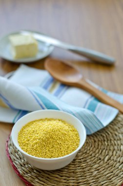 Millet, yuvarlak hasır bir kapta beyaz bir fincanda homurdanıyor ve bir tabakta tereyağı.