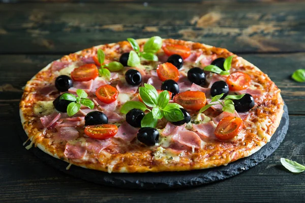 Pizza sobre una masa fina con aceitunas y albahaca fresca —  Fotos de Stock