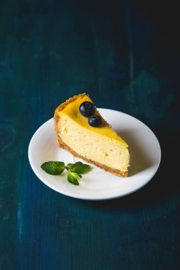 Bir dilim sarı peynirli kek ve taze yaban mersini.