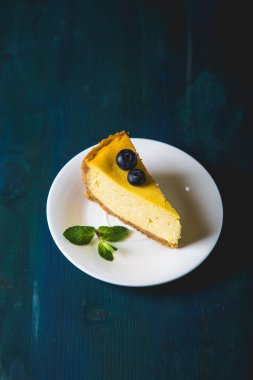 Bir dilim sarı peynirli kek ve taze yaban mersini.