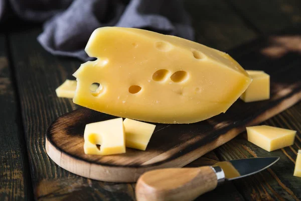 A piece of cheese on a cutting board