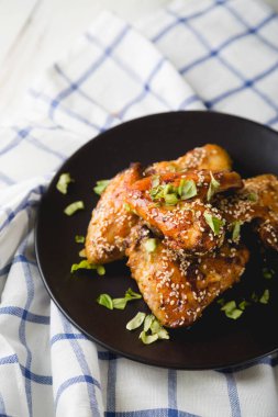 Susam tohumlu kızarmış tavuk kanatları ve doğranmış otlar.