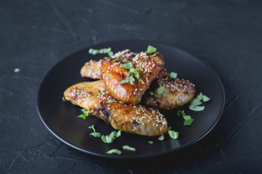 Susam tohumlu kızarmış tavuk kanatları ve doğranmış otlar.