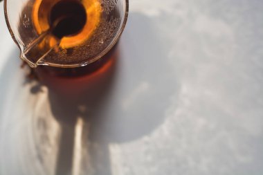 Bir tonluk beyaz zemin üzerinde koyu kahve dolu cam kap büyük ve alışılmadık gölgelerin yansıması..