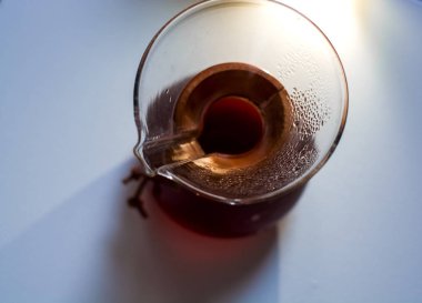 Bir tonluk beyaz zemin üzerinde koyu kahve dolu cam kap büyük ve alışılmadık gölgelerin yansıması..