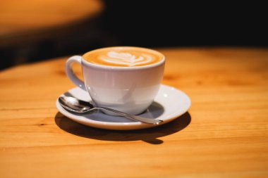 Kahve dükkanında seramik kupa ve ahşap boş masa üzerinde kapuçino. Latte sanatı. Sabah içkisi. Kafein.