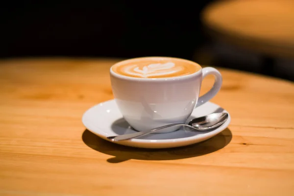 木製の空のテーブルの上にカプチーノとコーヒーショップでセラミックカップ ラテアート朝の飲み物だカフェイン — ストック写真