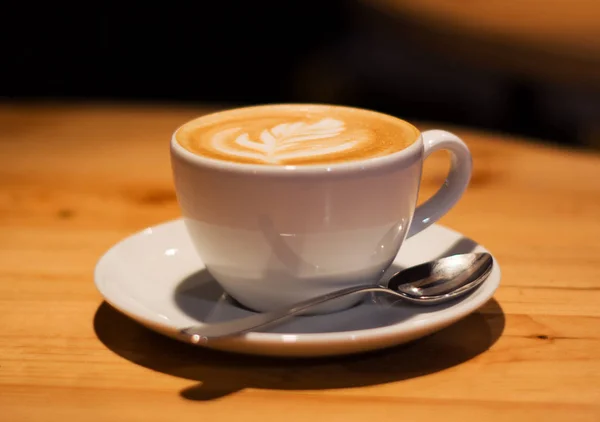 木製の空のテーブルの上にカプチーノとコーヒーショップでセラミックカップ ラテアート朝の飲み物だカフェイン — ストック写真