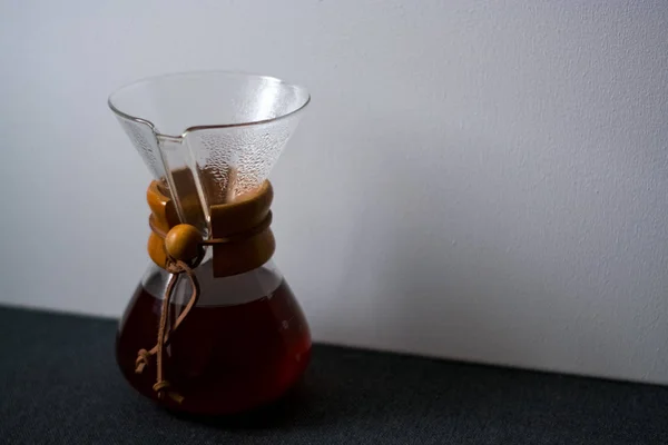 stock image Glass container filled with black coffee on one-ton white background with reflection of large and unusual shadows.