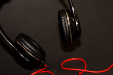 Siyah arka planda, kırmızı elementler ve kordon ile müzik dinlemek için büyük kulaklıklar. 