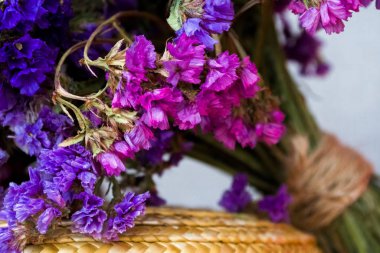 On summer straw hat, the boater, lies bouquet of field purple dry flowers bandaged with twine. Summer. Gift.