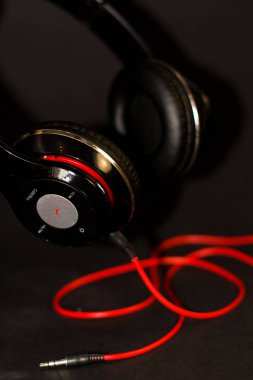 Siyah arka planda, kırmızı elementler ve kordon ile müzik dinlemek için büyük kulaklıklar. 