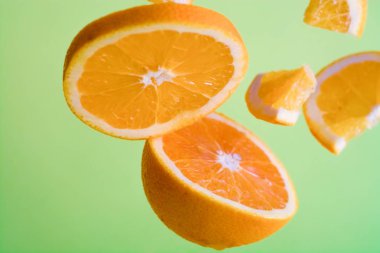 Yeşil parlak arka plan ve havada turuncu parçalar. Sağlıklı ve yararlı beslenme. Meyve ve turunçgiller. C vitamini diyeti..