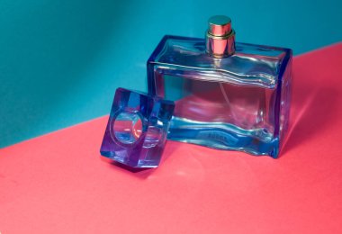 Pembe ve mavi arka plan. Cam, dikdörtgen mavi erkek parfümü şişesi. Üniseks. Kadınlar işte. Anlaşıldı. Katalog.