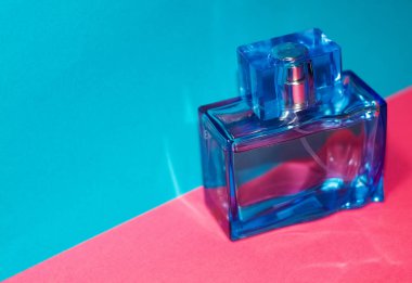 Pembe ve mavi arka plan. Cam, dikdörtgen mavi erkek parfümü şişesi. Üniseks. Kadınlar işte. Anlaşıldı. Katalog.