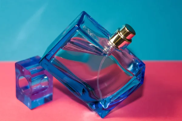 ピンクと青の背景 グラス メンズ香水の長方形の青いボトル 男女共同参画 女性だ クリスタルだ カタログ — ストック写真