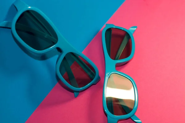 Jasnoróżowym Tle Leżą Okulary Przeciwsłoneczne Plastikowej Niebieskiej Ramce Ciemnymi Okularami — Zdjęcie stockowe