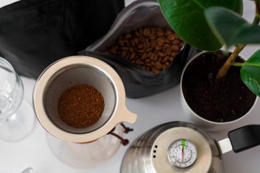 Beyaz arka plan, çaydanlıkta çiçek, bardakta koyu siyah doğal kahve Arabika fasulyesinden alternatif bir yöntemle hazırlanır..