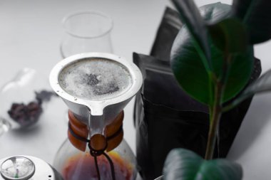 Beyaz arka plan, çaydanlıkta çiçek, bardakta koyu siyah doğal kahve Arabika fasulyesinden alternatif bir yöntemle hazırlanır..