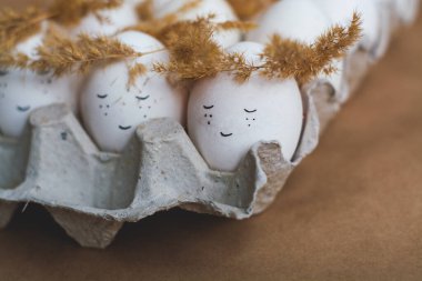 Mutlu Paskalyalar ve kırmızı tepside beyaz yumurtalar ve dikenli çelenklerden yapılmış şirin yüzler..